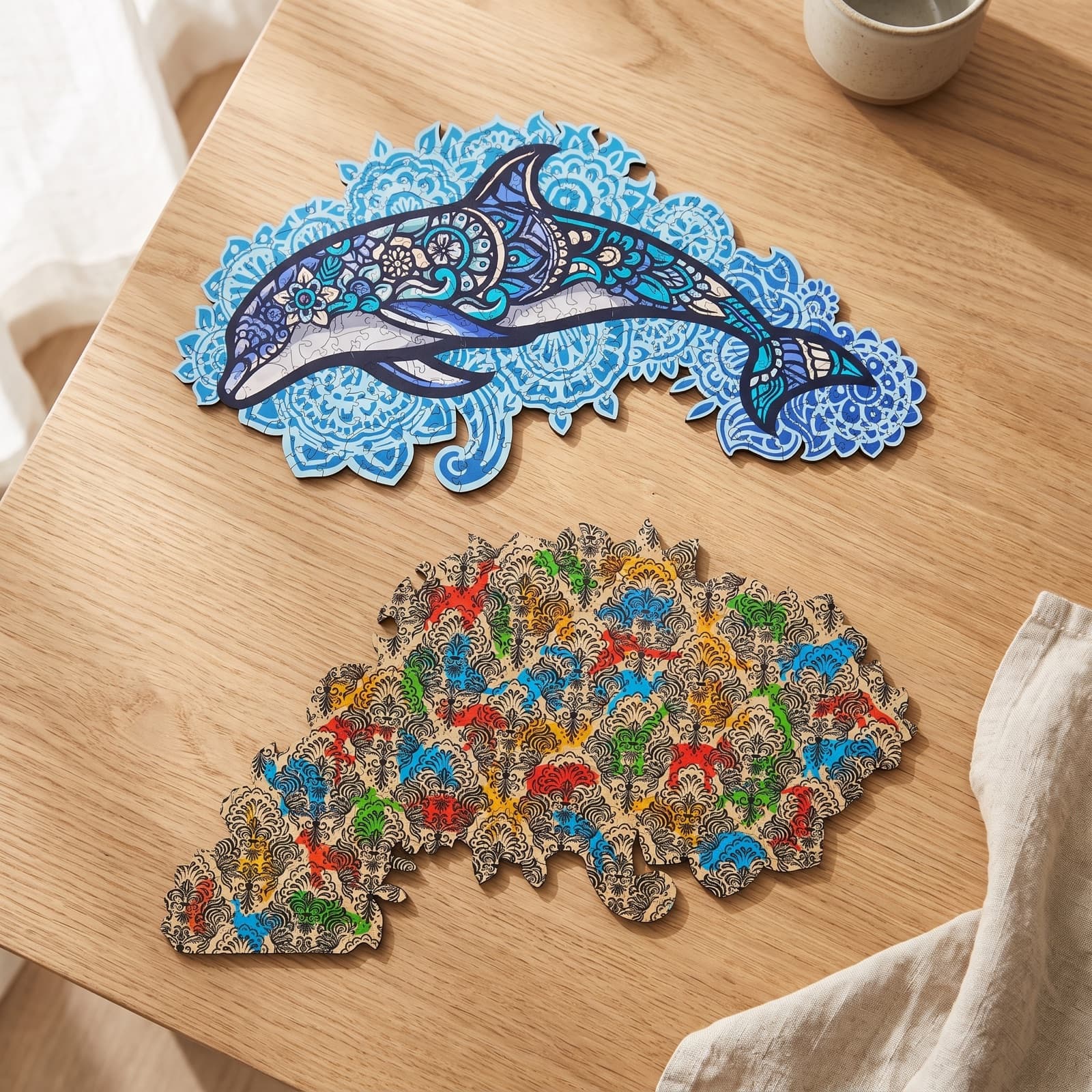 Les deux faces du puzzle Dauphin Majestueux posées sur une table en chêne : face dauphin mandala et face motifs abstraits